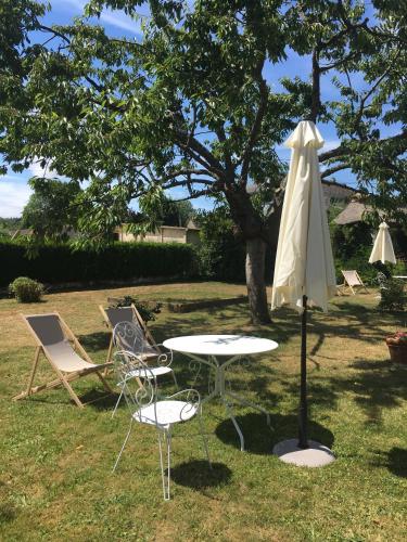 a table and chairs and an umbrella in the grass at La Romance et la Romanesque in Berville-sur-Mer
