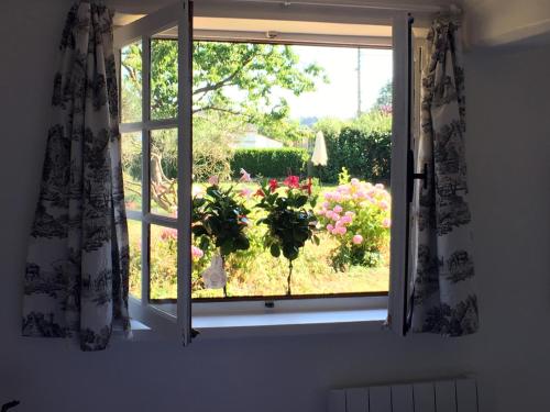 a window with a view of a garden with flowers at La Romance et la Romanesque in Berville-sur-Mer
