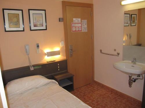 a bathroom with a bed and a sink and a phone at Hostal La Vila in Olot