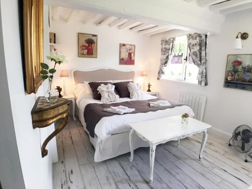 a bedroom with a white bed and a table at La Romance et la Romanesque in Berville-sur-Mer