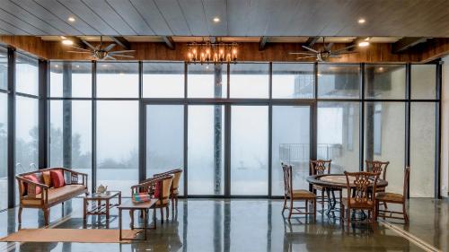 a dining room with a table and chairs and windows at SaffronStays Falcon Hill, Lonavala - luxury villa with infinity pool near Lion's Point in Lonavala