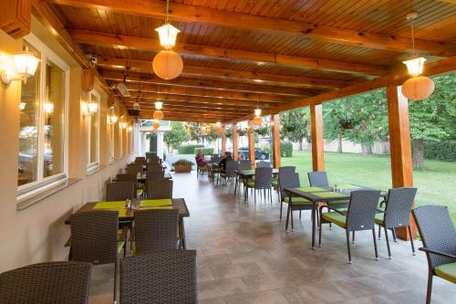 un restaurante vacío con mesas, sillas y luces en Lipa Hotel és Étterem, en Szentgotthárd
