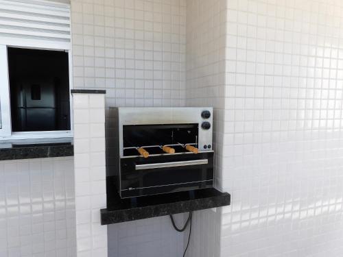 a wall mounted oven in a bathroom with white tiles at Arraial do Cabo in Arraial do Cabo