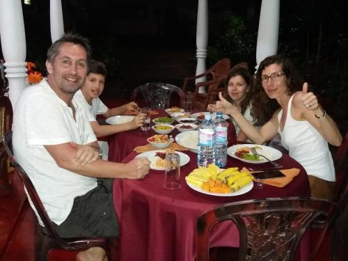 a group of people sitting around a table with food at Palitha Homestay in Sigiriya