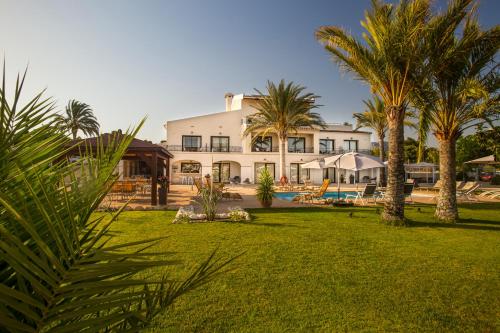a large white house with palm trees and a yard at Aparthotel Camp El Planet in L’Alfàs del Pi