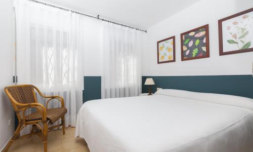 Apartments Mar de Tossa في توسا ذي مار: غرفة نوم بسرير كبير وكرسي