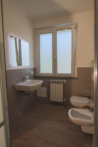 a bathroom with a sink and a toilet and two windows at Santa Caterina in Levanto