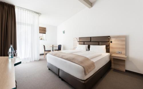 a bedroom with a large bed and a table at Donna Hotel Klosterhof in Neukirchen beim Heiligen Blut