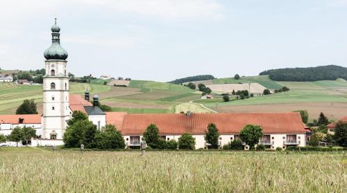 a church with a tower in the middle of a field at Donna Hotel Klosterhof in Neukirchen beim Heiligen Blut