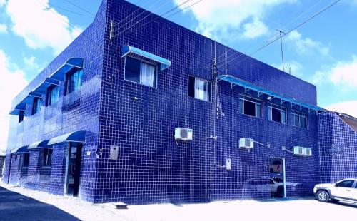 馬塞約的住宿－POUSADA OLÍMPIA，前面有一辆汽车停着的蓝色砖砌建筑