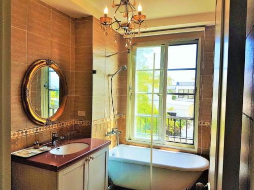 baño con bañera, lavabo y ventana en Haut Rhin Villa en Zhuangwei