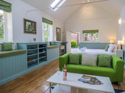 a living room with a bed and a green couch at Bluebell Studio in Saxmundham