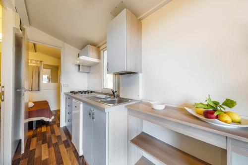a kitchen with a sink and a bowl of fruit on the counter at Camping&Village Le Cernie in Lotzorai