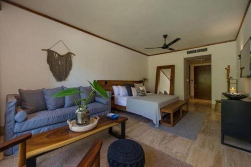 a living room with a couch and a bed at Kimpton Aluna Resort Tulum by IHG in Tulum