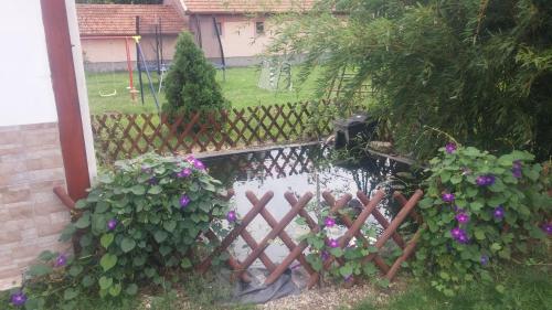 a garden with a fence and a pond with purple flowers at Rákóczi Vendégház in Poroszló