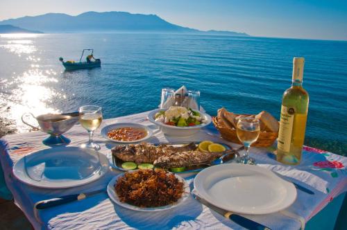 a table with food and a bottle of wine and the ocean at Akrogiali in Kissamos