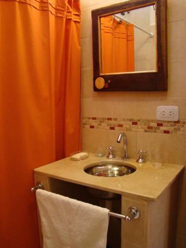 a bathroom with a sink and an orange shower curtain at Rinconcito en Tilcara in Tilcara