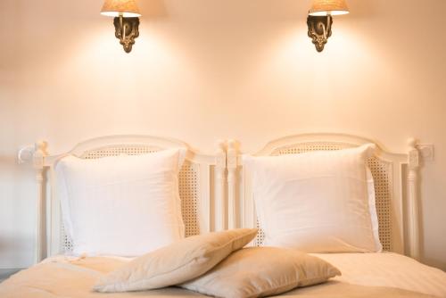 a white bed with two pillows and two lights at Les suites du 17 in Aigues-Mortes
