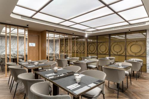a restaurant with tables and chairs and windows at Room Mate Collection Gorka, San Sebastián in Donostia-San Sebastián