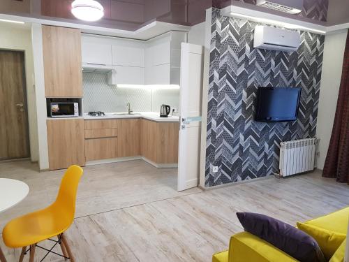 a kitchen and a living room with a table and a yellow chair at Квартира Lux біля Саржиного Яру in Kharkiv