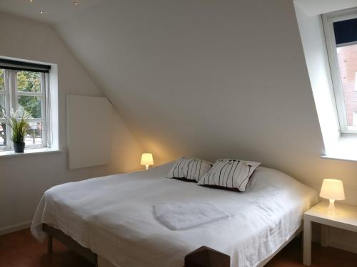 a bedroom with a white bed with two windows at Aalborg City Rooms ApS in Aalborg