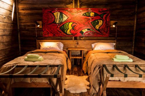 two beds in a room with a painting on the wall at Las Pitras Lodge in Epuyén