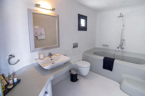 a white bathroom with a sink and a bath tub at Ambassador Aegean Luxury Hotel & Suites in Akrotiri
