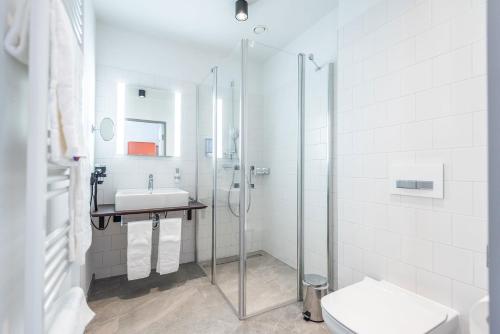 a bathroom with a shower and a sink and a toilet at Glashütte Bed+Breakfast in Barnbäch
