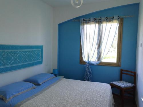 Dormitorio azul con cama y ventana en Agriturismo "PIRASTRERI" en Siniscola