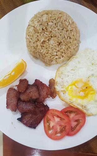 a plate of breakfast food with eggs bacon and tomatoes at Bella Vita Guest House in Coron