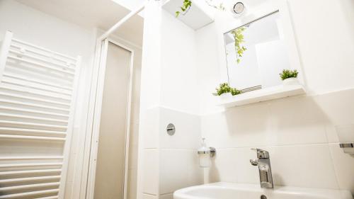 a white bathroom with a sink and a mirror at LikeHome Milano - Via Crema in Milan