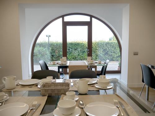 皮耶特雷尔奇纳Villa dei Tigli Resort & SPA的餐厅里有一扇拱形窗户，摆放着桌椅。