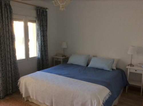 1 dormitorio con cama con sábanas azules y ventana en Los Cipryses, en La Herradura