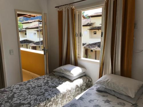een kleine slaapkamer met een bed en een raam bij Linda casa em condomínio in Paraty