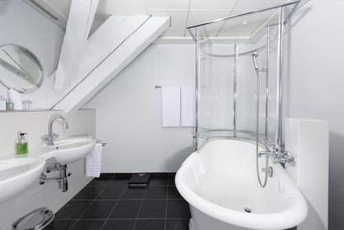 a bathroom with a sink and a tub and a toilet at Hotel Stadthaus in Burgdorf