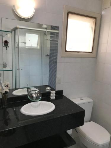 een badkamer met een wastafel, een toilet en een spiegel bij Linda casa em condomínio in Paraty