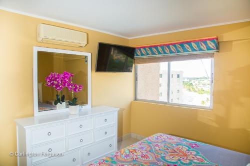 a bedroom with a dresser and a window with a mirror at Turtle Beach Towers in Ocho Rios