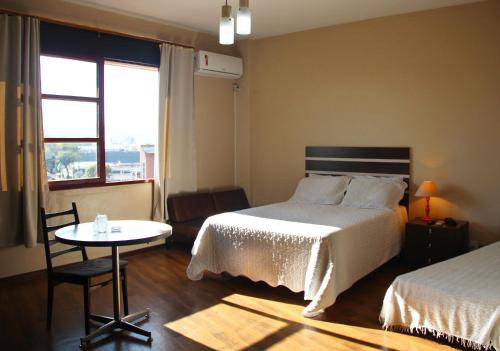 Schlafzimmer mit einem Bett, einem Tisch und einem Fenster in der Unterkunft Opera Hotel in Pôrto União