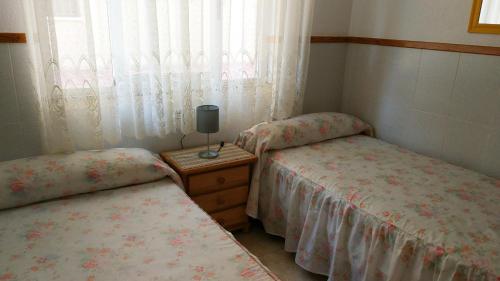 two twin beds in a room with a window at Viviendas Moreno Mar Menor in Santiago de la Ribera