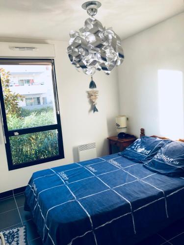 - une chambre avec un lit bleu et un lustre dans l'établissement Appartement 1 ROYAL VILLEROY, à Sète