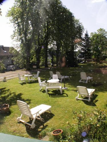a group of chairs and tables in the grass at Thermen Hotel Pension Villa Holstein in Bad Salzuflen