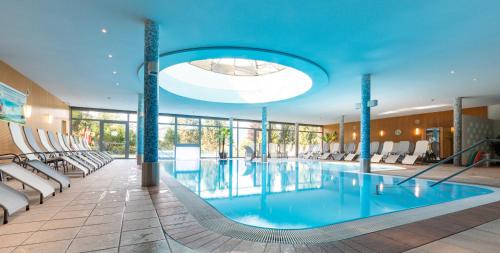 a large swimming pool with chairs and a blue ceiling at Hotel-Restaurant Grimmingblick in Bad Mitterndorf