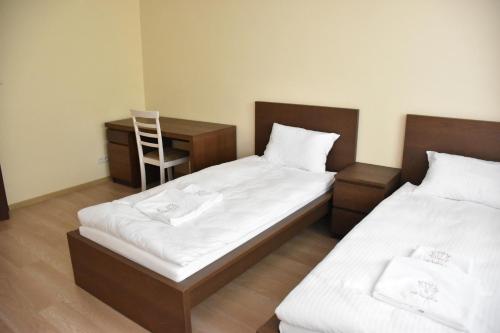 ジェロナ・グラにあるApartamenty Drzewnaのデスクと椅子が備わる客室内のベッド2台