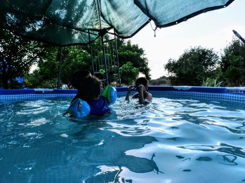 two children playing in a swimming pool at Country lodging in Manot in Manot