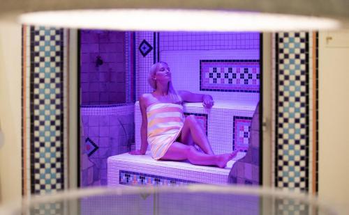 a woman sitting on a shelf in a purple bathroom at Hotel-Restaurant Grimmingblick in Bad Mitterndorf