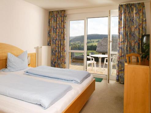 a bedroom with a bed and a view of a balcony at Wohnpark Schwarzwaldblick Bernau in Bernau im Schwarzwald