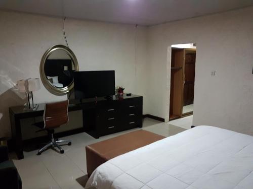 a bedroom with a bed and a desk and a mirror at Hotel Cabenda in Freetown