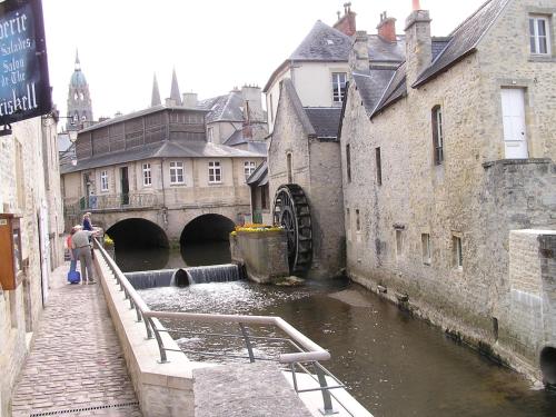a canal in a city with a bridge and buildings at Le Chat Qui Veille in Bayeux