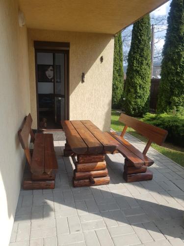 a wooden picnic table and two benches on a patio at Domek Przy Źródełku in Muszyna