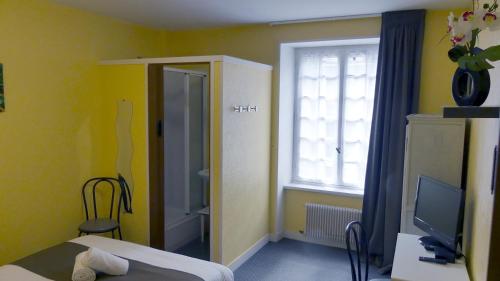 a room with a bed and a window and a television at Hôtel Duguesclin in La Haye-Pesnel